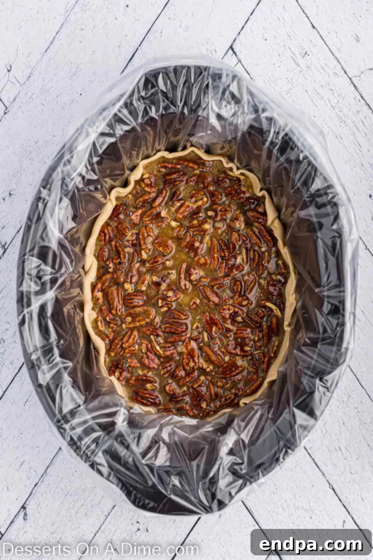 Pecan pie poured into pie crust. The liquid pecan pie filling being carefully poured into the crust-lined slow cooker.