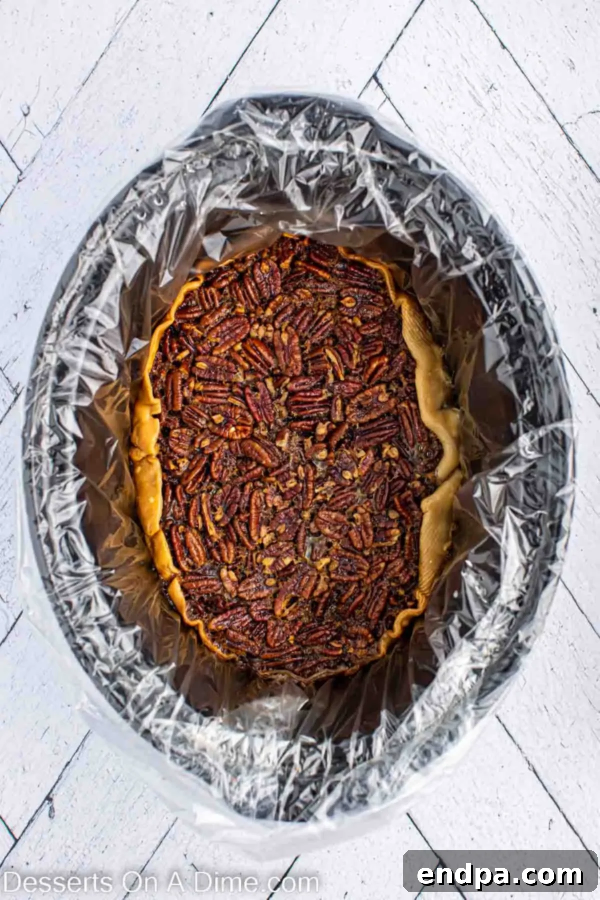 Pecan Pie cooked and ready to set in slow cooker. A cooked pecan pie sitting in a slow cooker, looking golden brown and ready to cool.