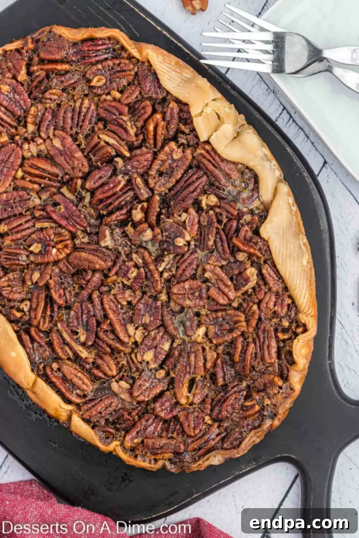 Pecan Pie removed from crock pot and ready to slice. A whole Crock Pot Pecan Pie, perfectly cooked and removed from the slow cooker, sitting on a wooden board ready to be sliced.
