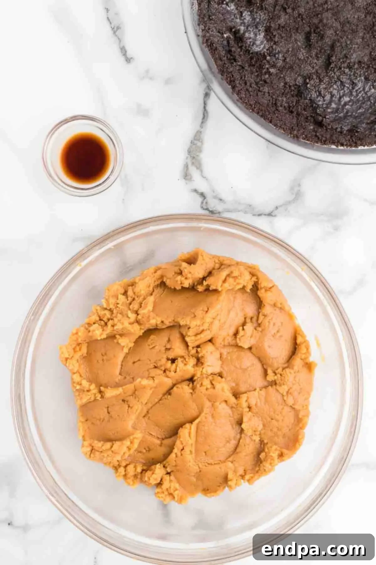 Beating softened cream cheese and creamy peanut butter together in a large mixing bowl with an electric mixer. The mixture is smooth and light yellow, indicating it's well combined.