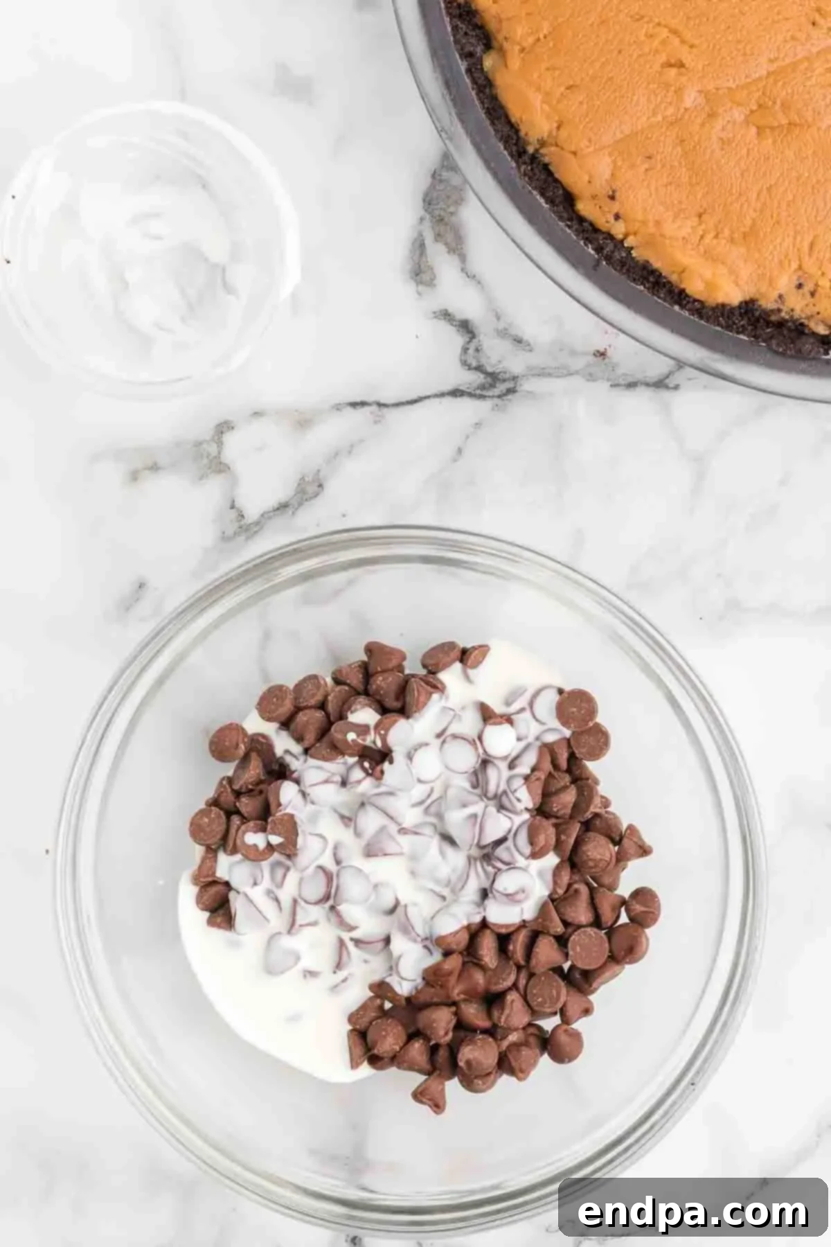 Melting milk chocolate chips and heavy cream in a medium microwave-safe bowl. The chocolate is partially melted and being stirred with a spoon, becoming a smooth ganache.