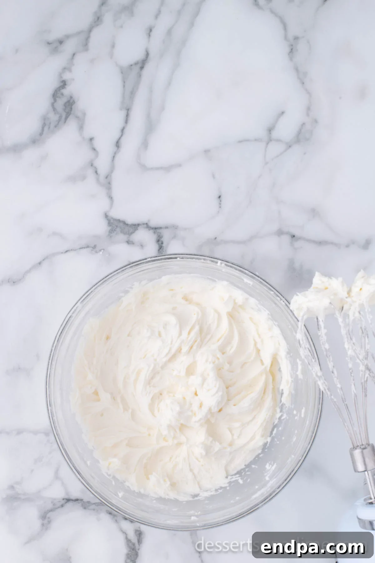 Ho-Ho-Ho Brownie Hats 4 Softened unsalted butter being beaten in a large mixing bowl with an electric hand mixer until light and creamy, ready for the frosting ingredients.