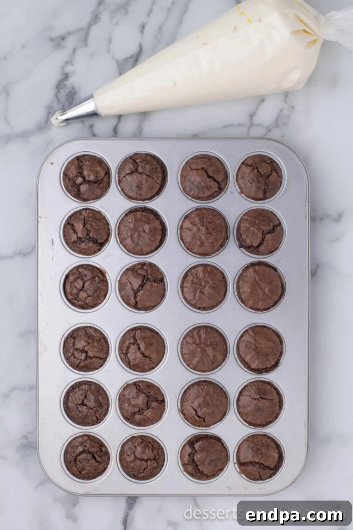 Ho-Ho-Ho Brownie Hats 5 White buttercream frosting being carefully scooped into a clear piping bag, secured at the top, ready for precise decoration.