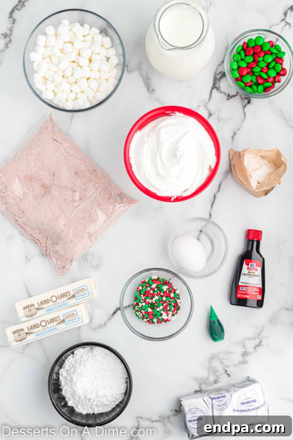Assortment of ingredients for Christmas lasagna, including red velvet cake mix, marshmallows, candy, cream cheese, vanilla, and butter.