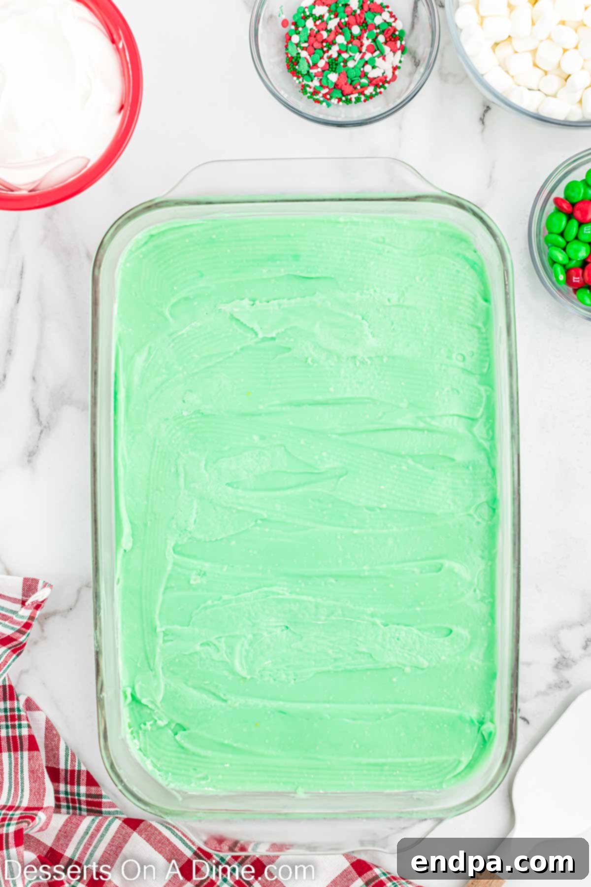The green pudding layer spread over the white cheesecake layer in the baking dish.