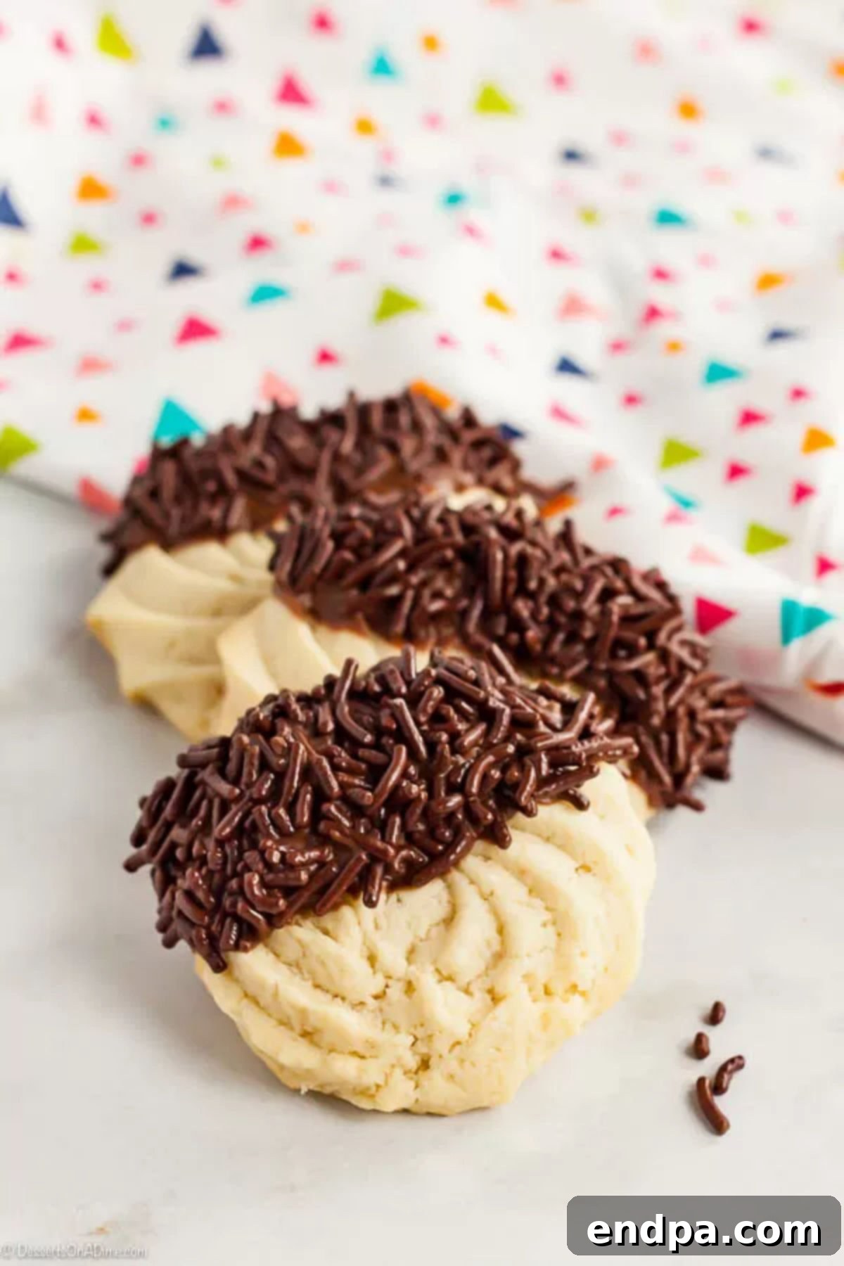 With just a few ingredients, Butter Cookies Recipe comes together quickly for a tasty and gorgeous treat. Easy butter cookies are so pretty and delicious. Two enticing butter cookies, artfully dipped in rich chocolate frosting and generously sprinkled with chocolate decorations, presented on a bright white background.