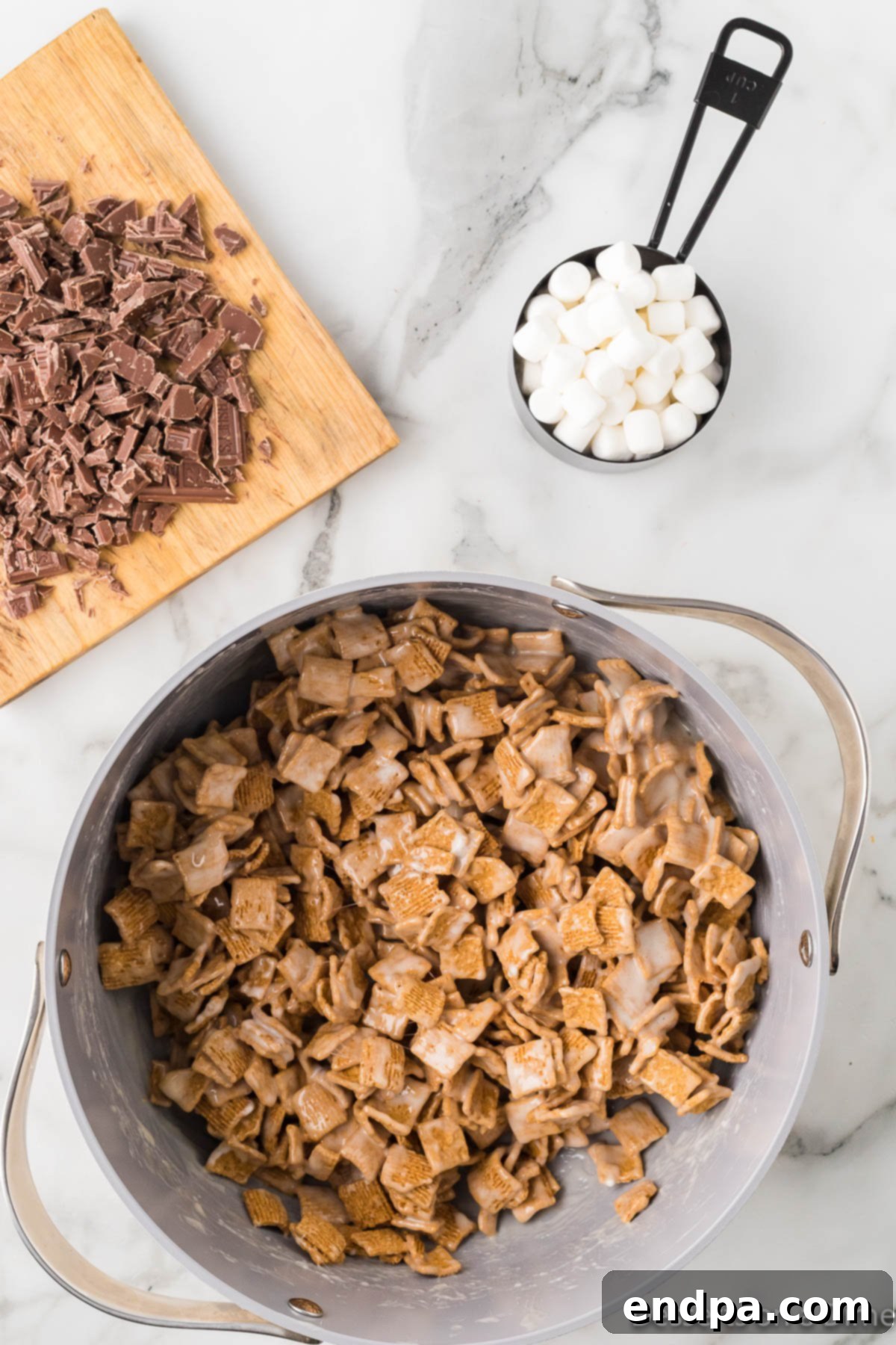 Golden Grahams cereal being stirred into the melted marshmallow mixture in a pot.