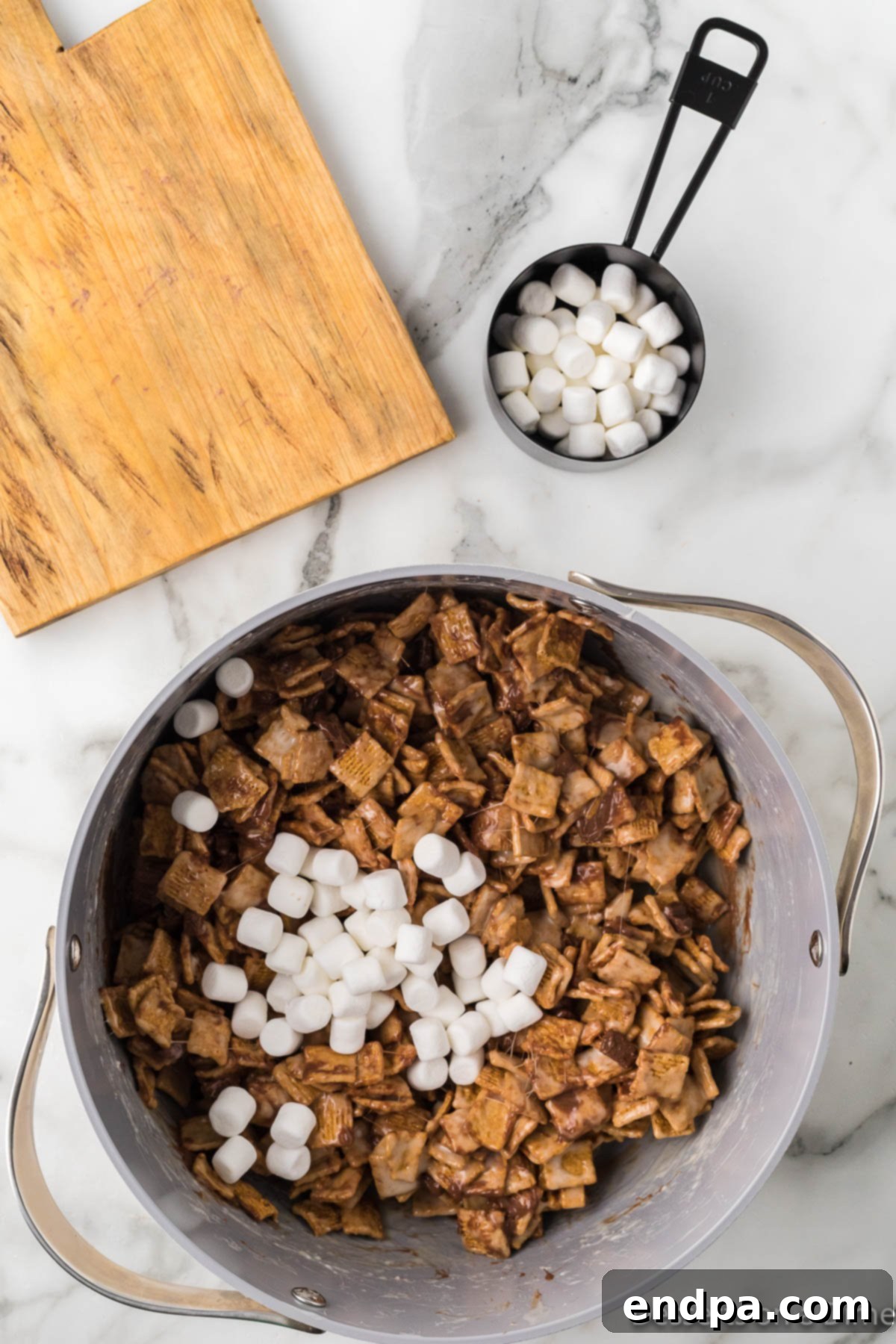 Half of the reserved mini marshmallows being folded into the warm cereal mixture.