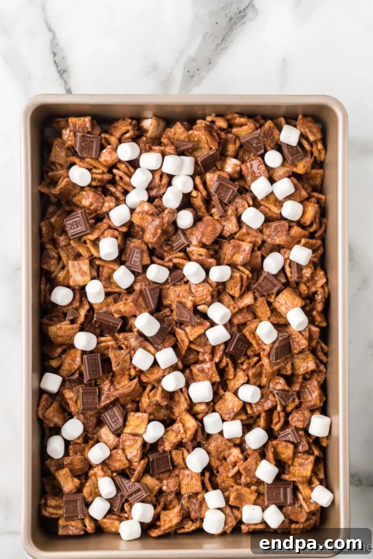 A baking dish with the Golden Graham s'mores mixture spread evenly, ready for toppings.