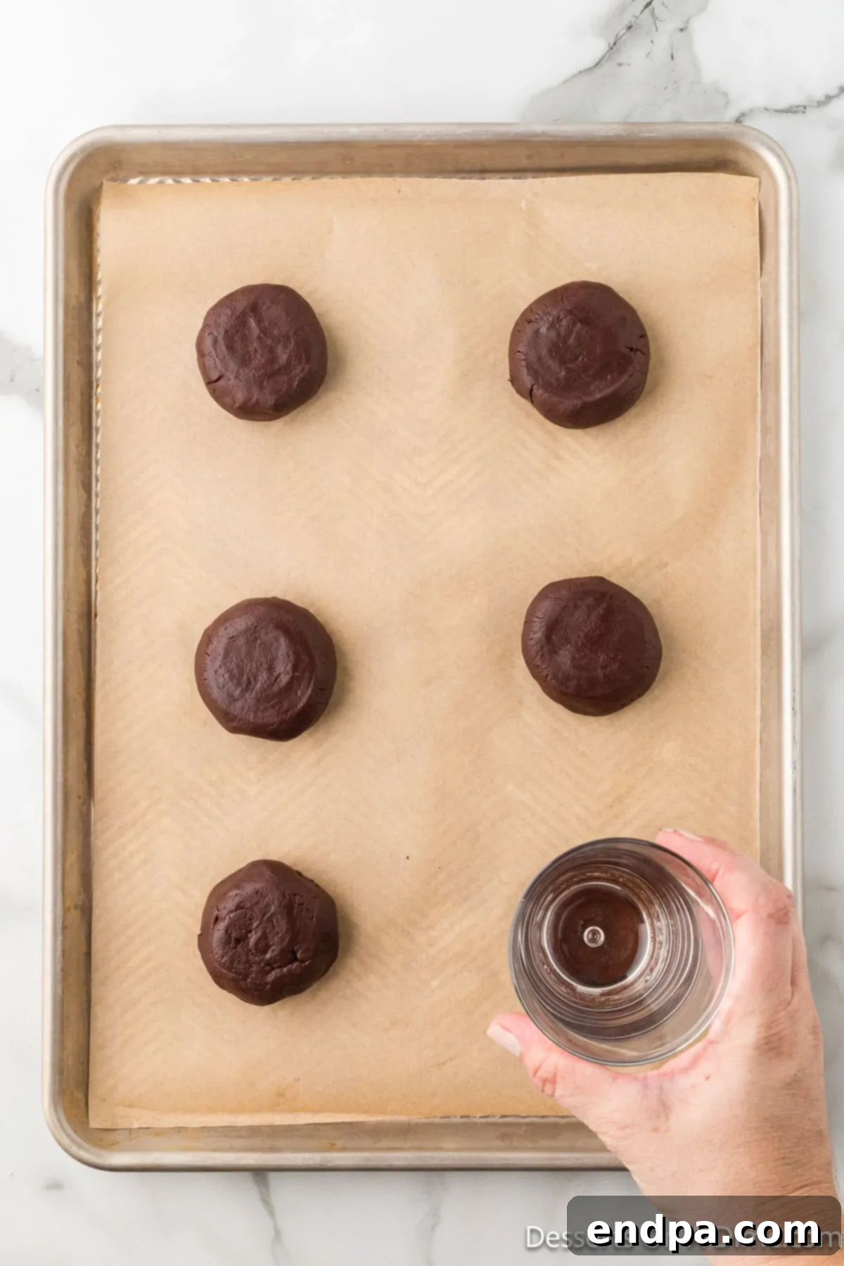 Crumbl Style Buckeye Brownie Cookies 15 Cookie dough balls flattened with a glass.