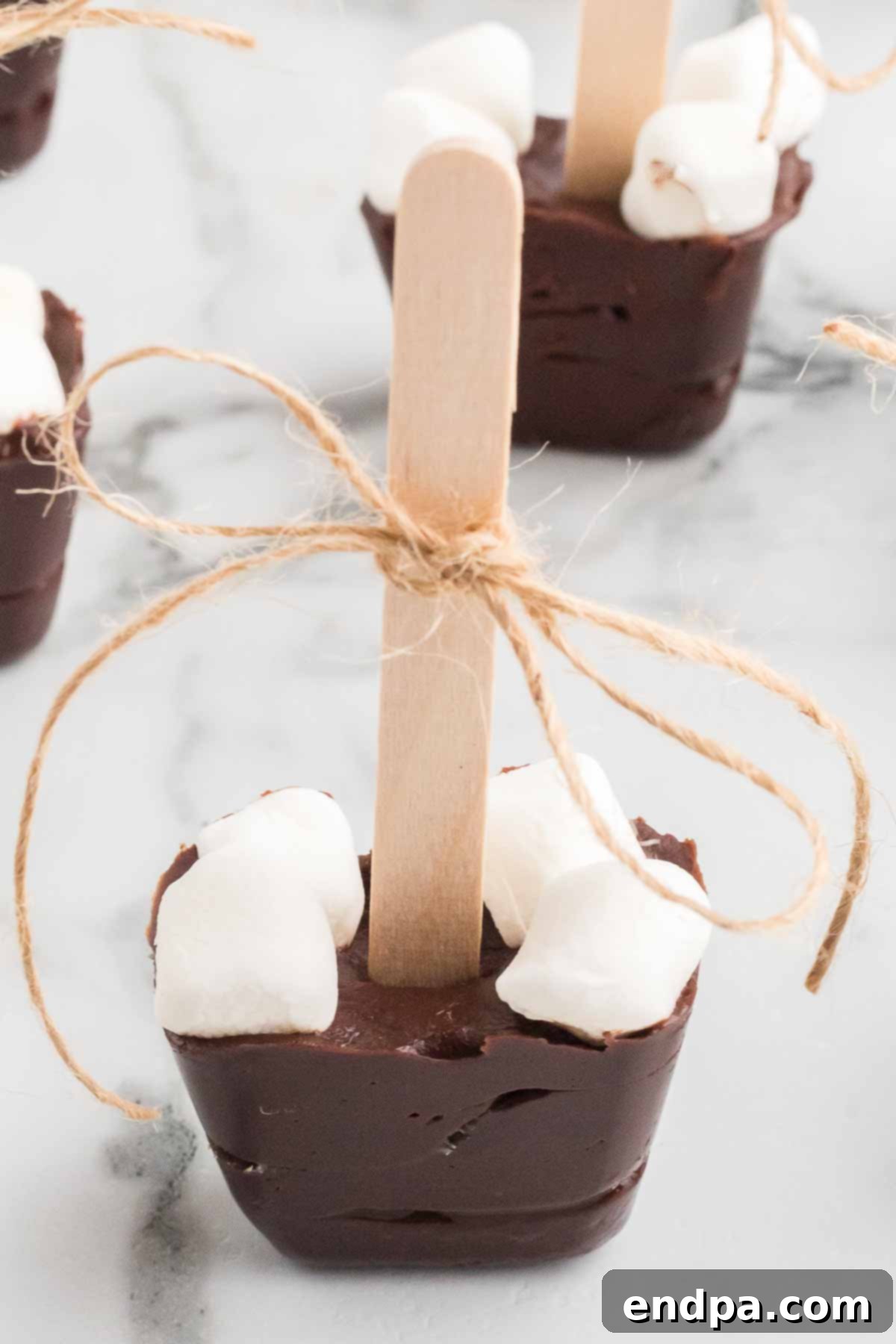 Hot chocolate on a stick ready to enjoy in a mug, topped with marshmallows.