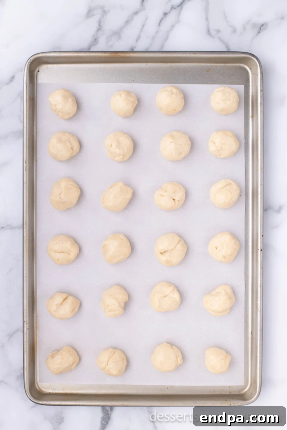 Krispy Kreme Donut Bites 15 Shaped donut holes arranged on a baking sheet, waiting for their turn to be fried.
