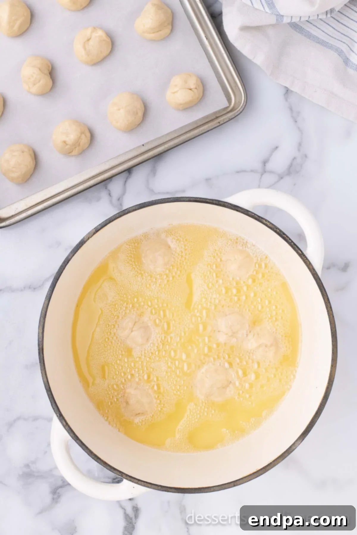 Krispy Kreme Donut Bites 16 Donut holes frying to a golden brown in hot oil within a stockpot, showing the active cooking process.