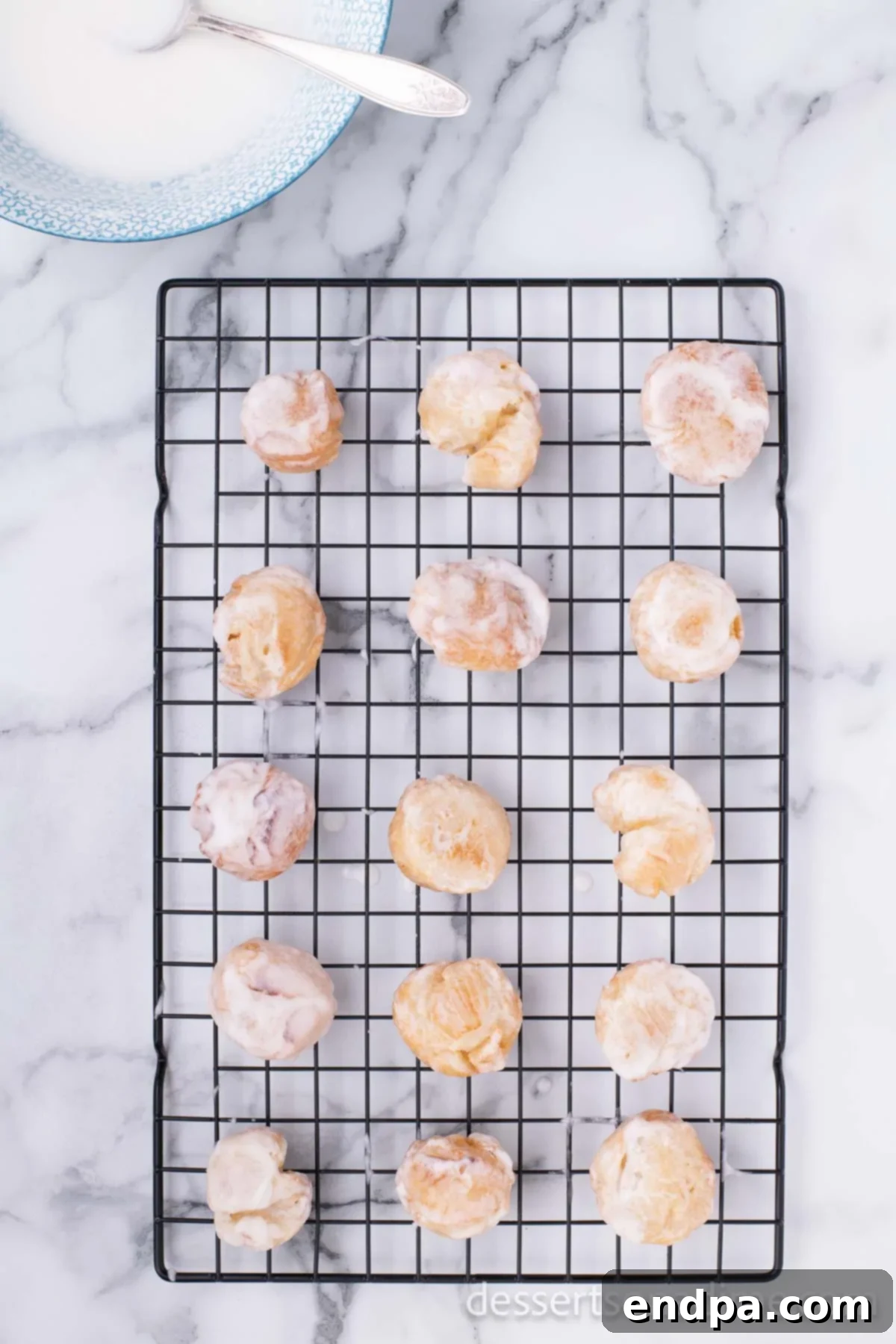 Krispy Kreme Donut Bites 19 Glazed donut holes cooling on a wire rack, allowing the glaze to set and excess to drip away.