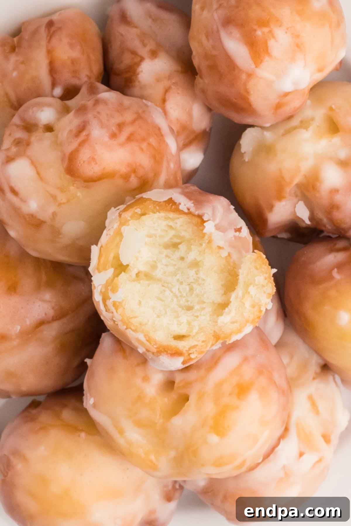 Krispy Kreme Donut Bites 20 A generous cluster of freshly made, perfectly glazed Krispy Kreme Donut Holes, showcasing their fluffy texture and enticing shine.