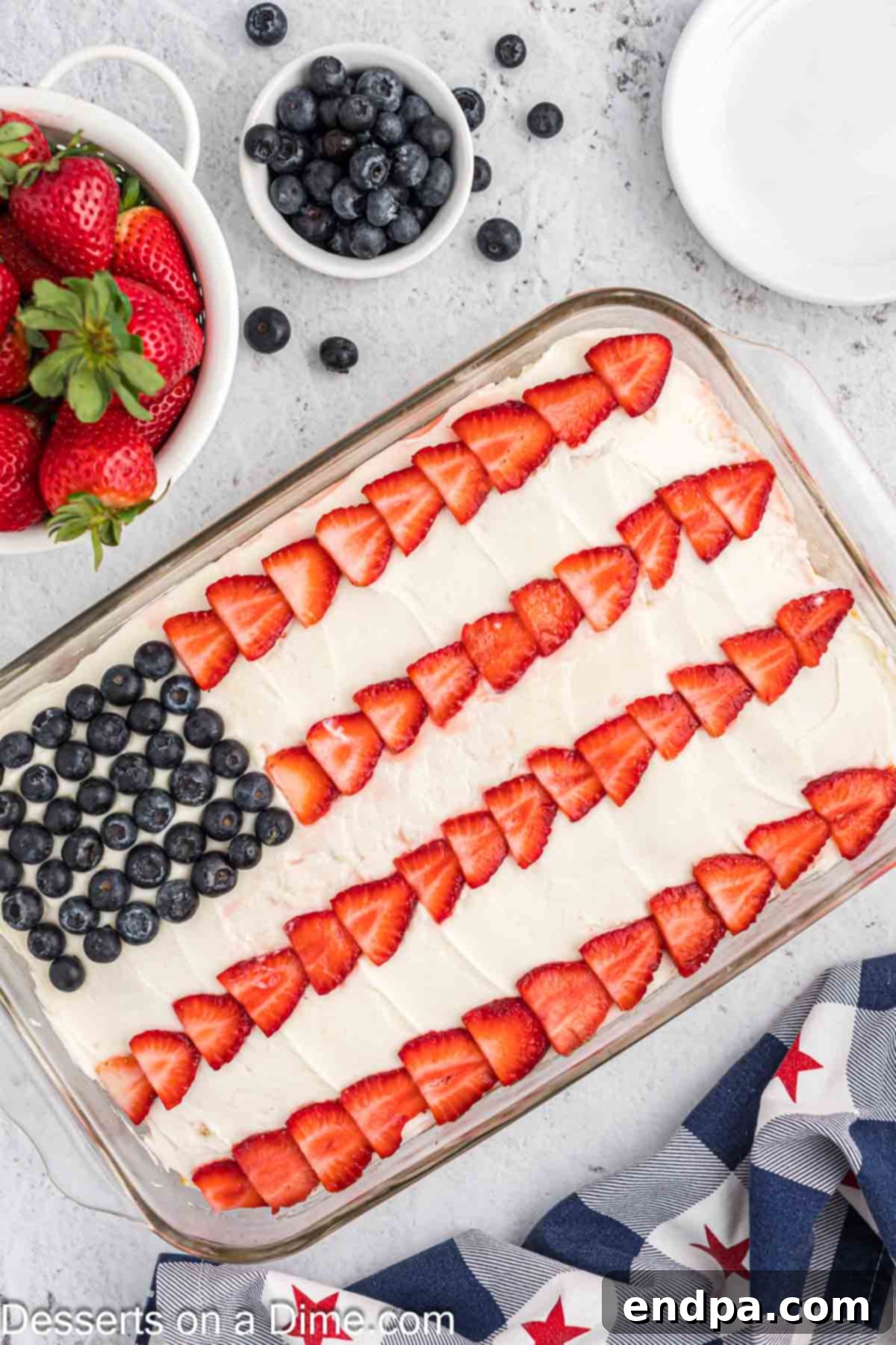 A stunning American Flag Cake, beautifully decorated with fresh blueberries and sliced strawberries, ready to be enjoyed at a patriotic celebration.