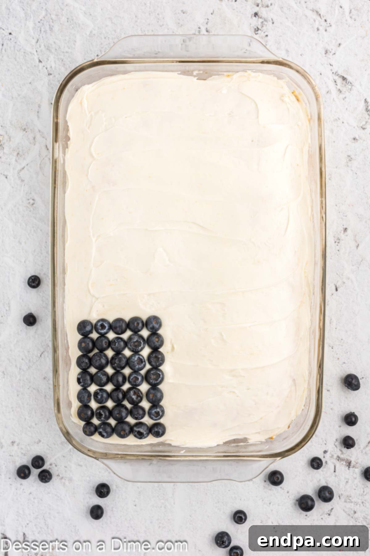 A cake with vanilla icing, partially decorated with blueberries in the upper left corner forming the 'star' field.