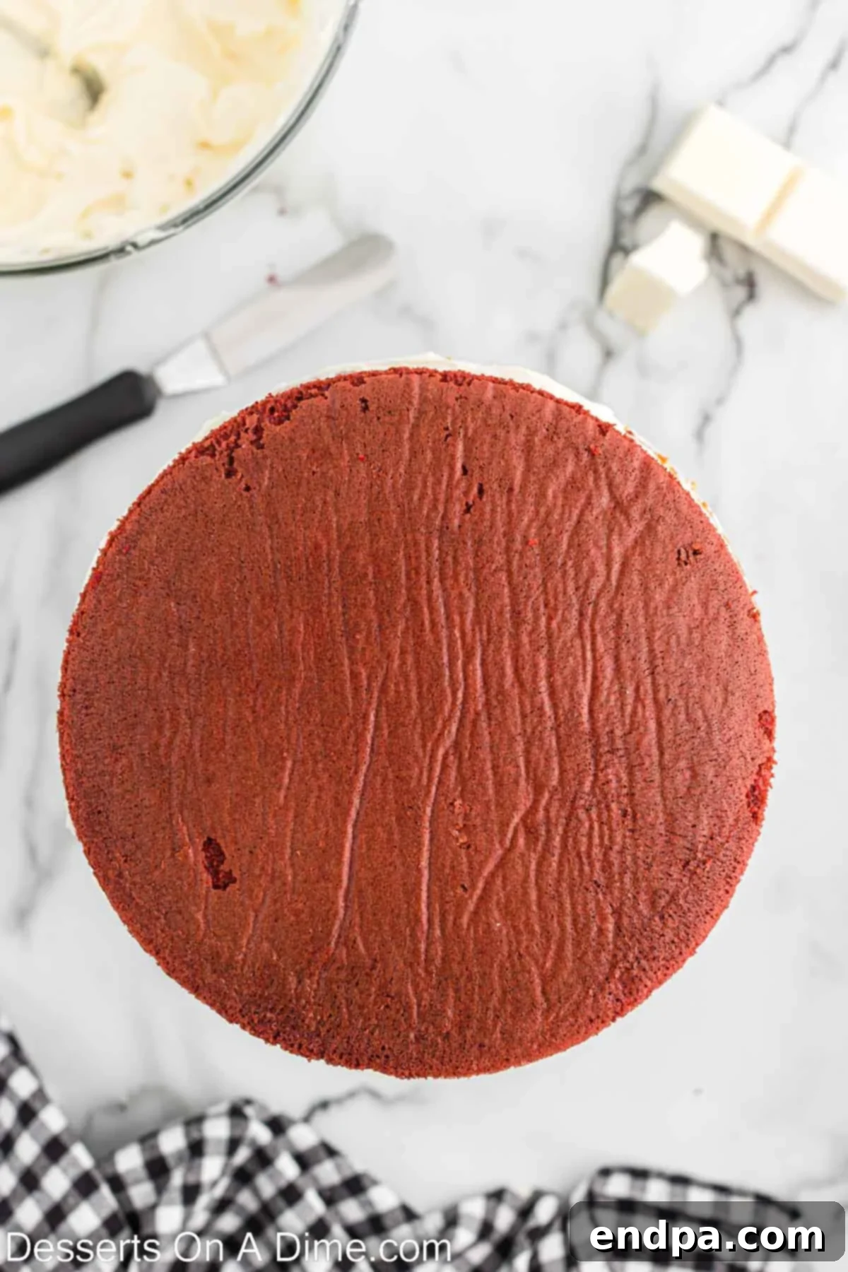 Red velvet cake layers being leveled with a serrated knife for even stacking.