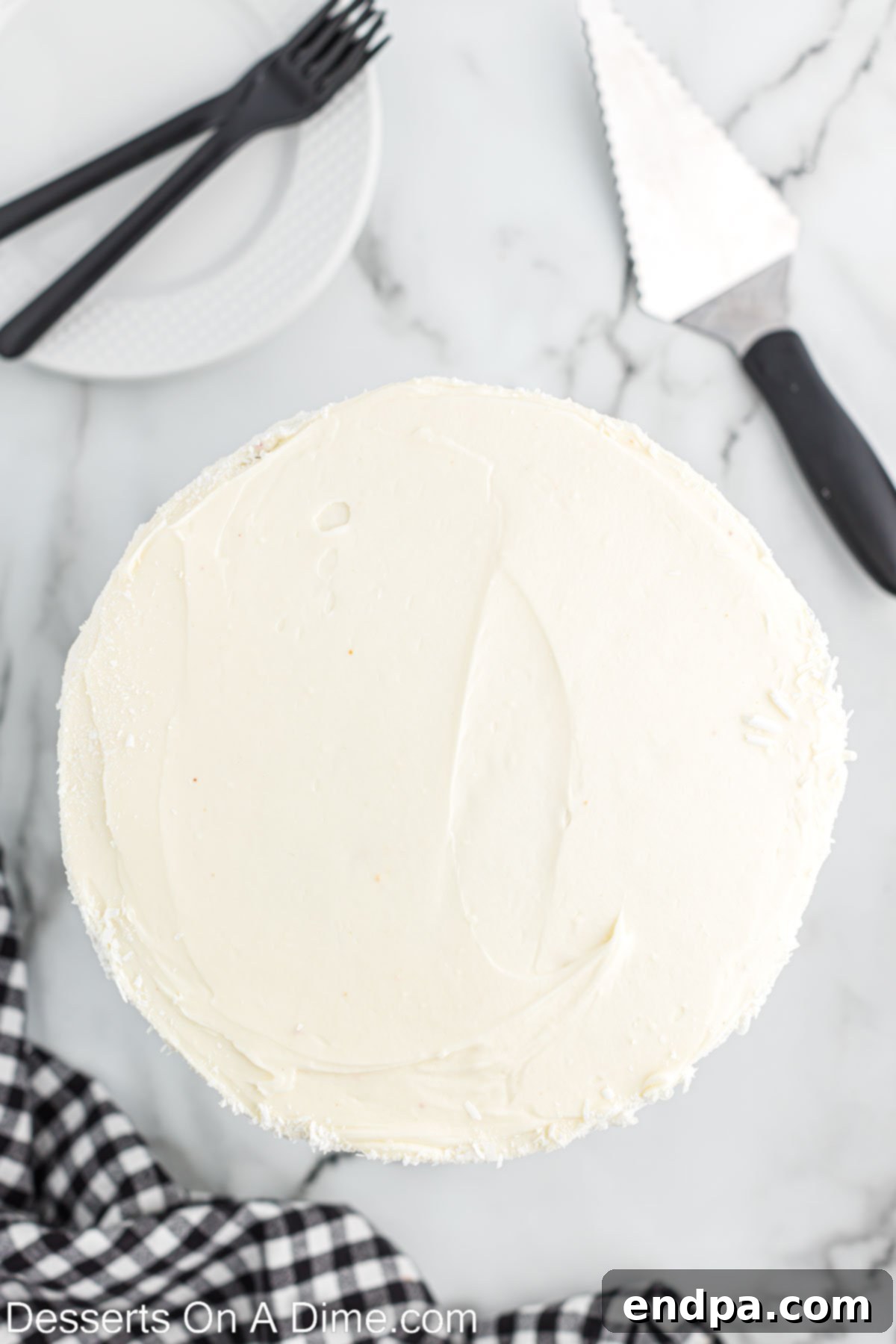 First red velvet cake layer topped with a generous layer of cream cheese frosting on a serving platter.