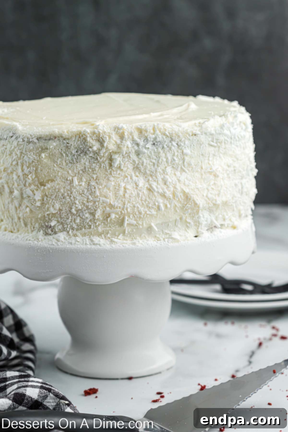 The fully assembled Red Velvet Cheesecake on a cake stand, revealing its beautiful layered structure.