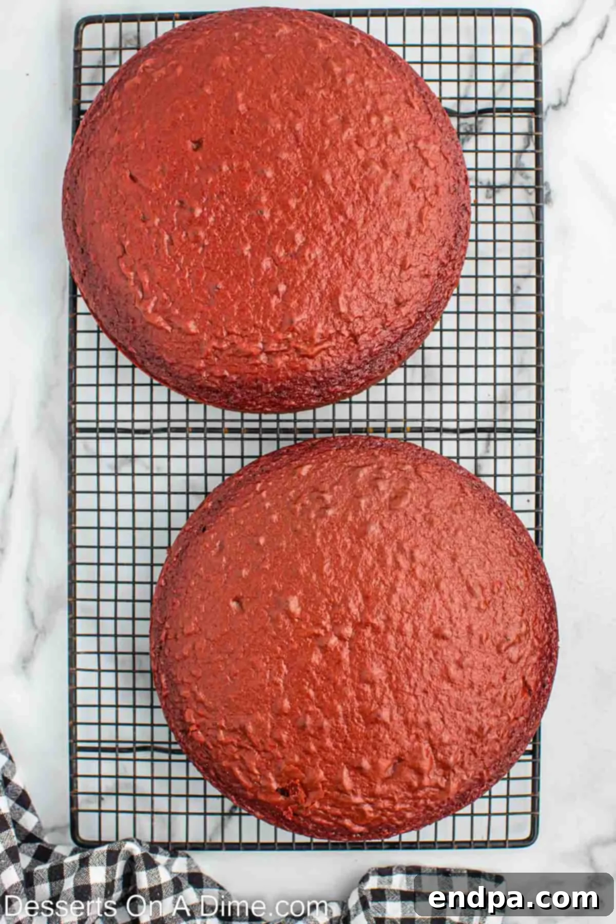 Two vibrant red velvet cakes cooling on a wire rack after baking.