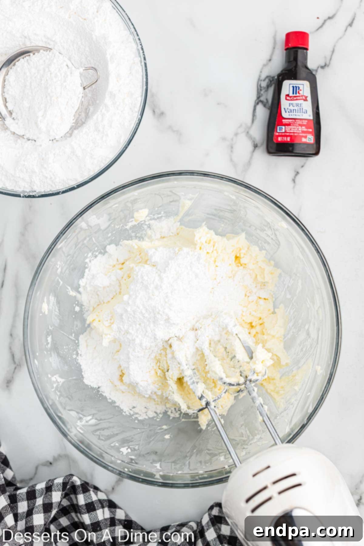 Mixing bowl with cream cheese, sugar, and other cheesecake ingredients being beaten together.