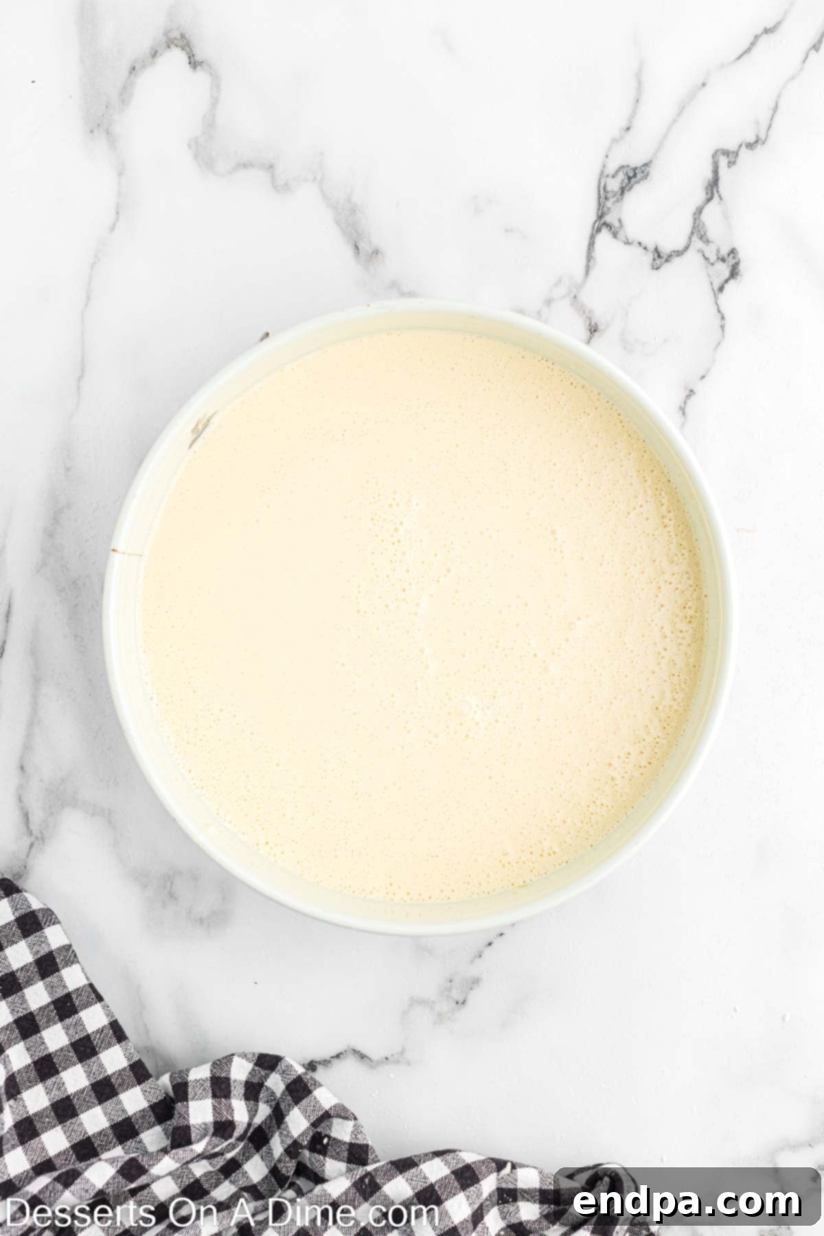 Smooth cheesecake batter combined in a large mixing bowl, ready for baking.