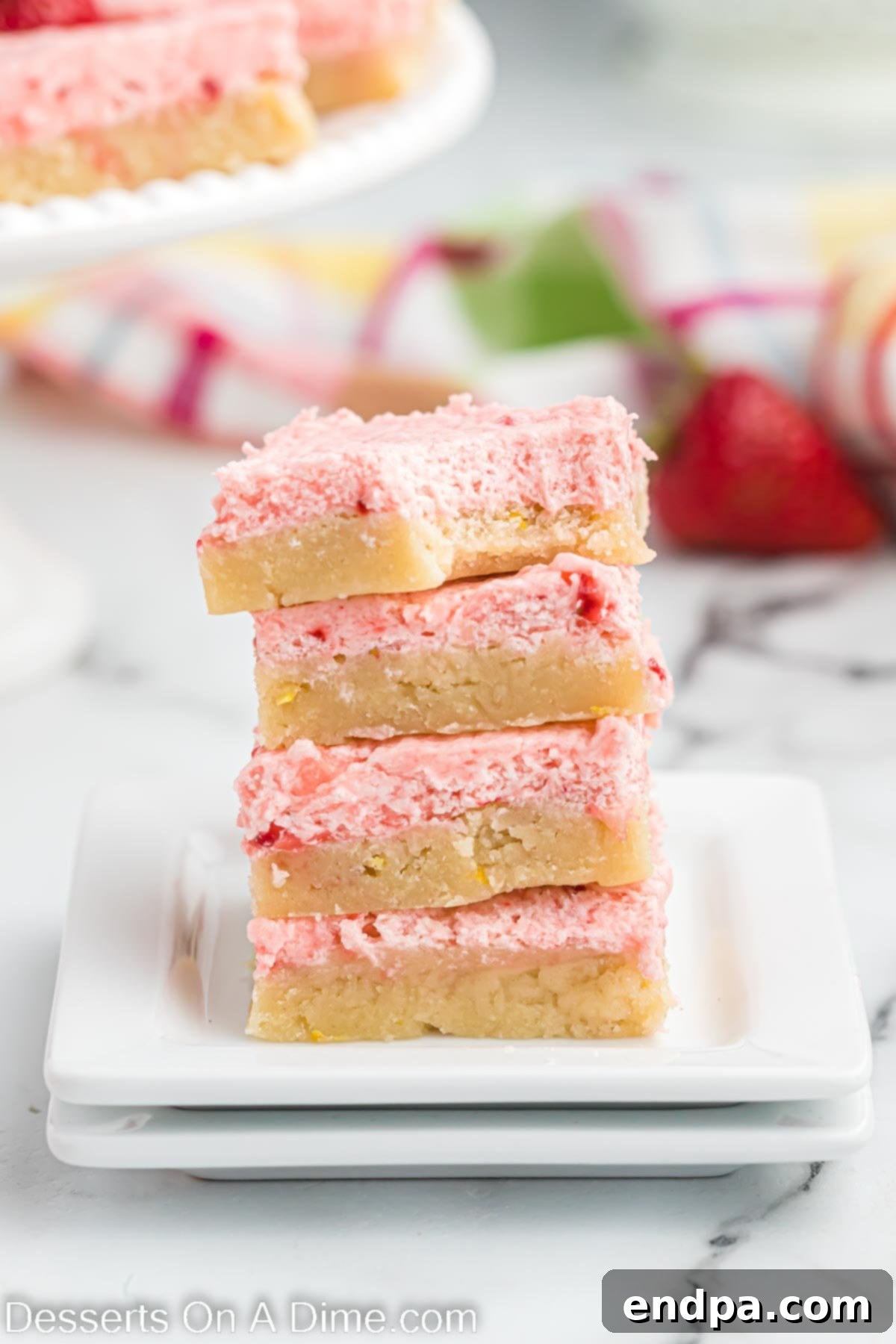Stacked Strawberry Lemonade Sugar Cookie Bars showcasing the lemon cookie base and pink strawberry frosting.