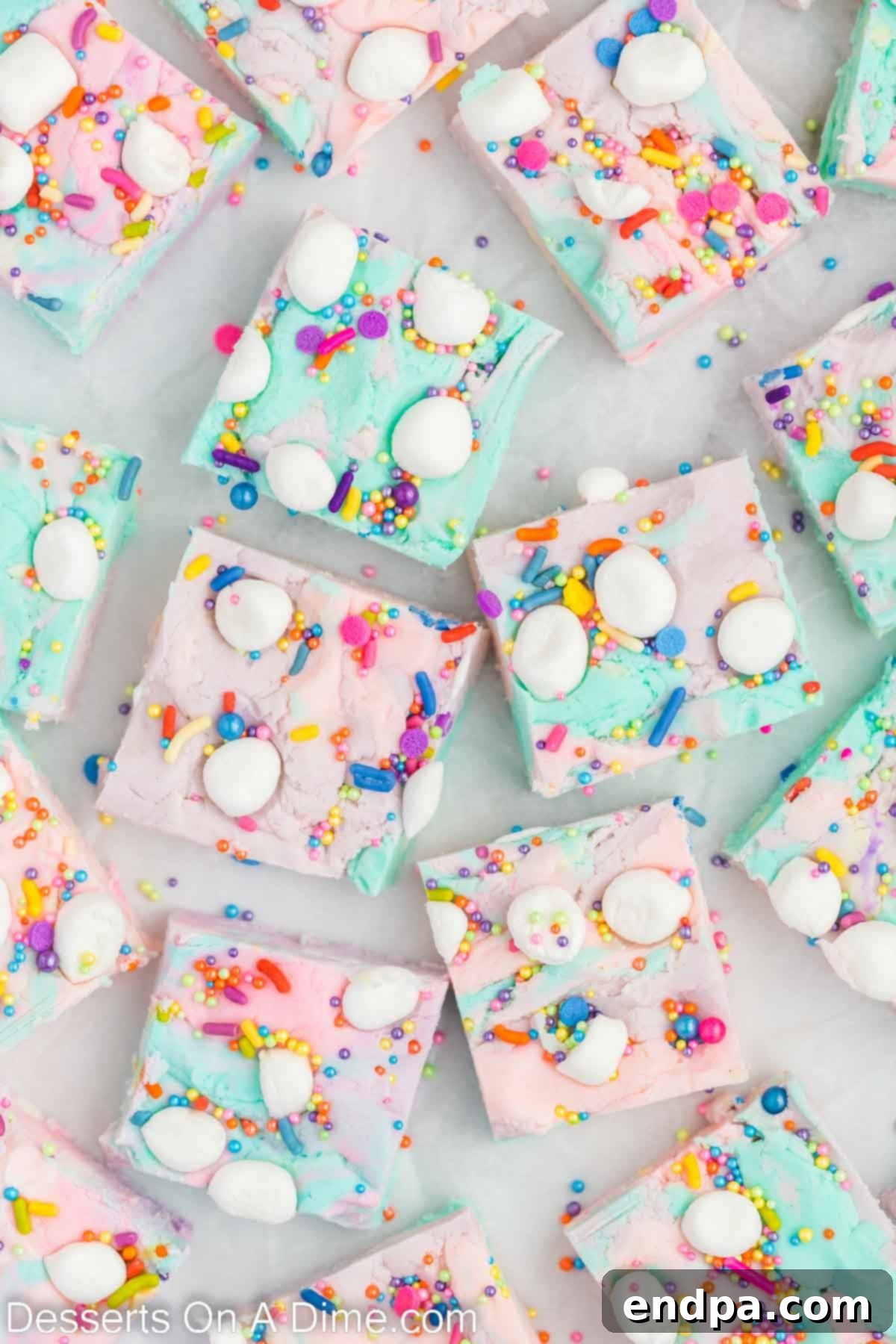 Enchanted Unicorn Swirl Fudge 10 Close-up of numerous squares of Unicorn Fudge, each displaying unique swirls of pink, purple, and blue, topped with colorful sprinkles, arranged neatly on a surface.