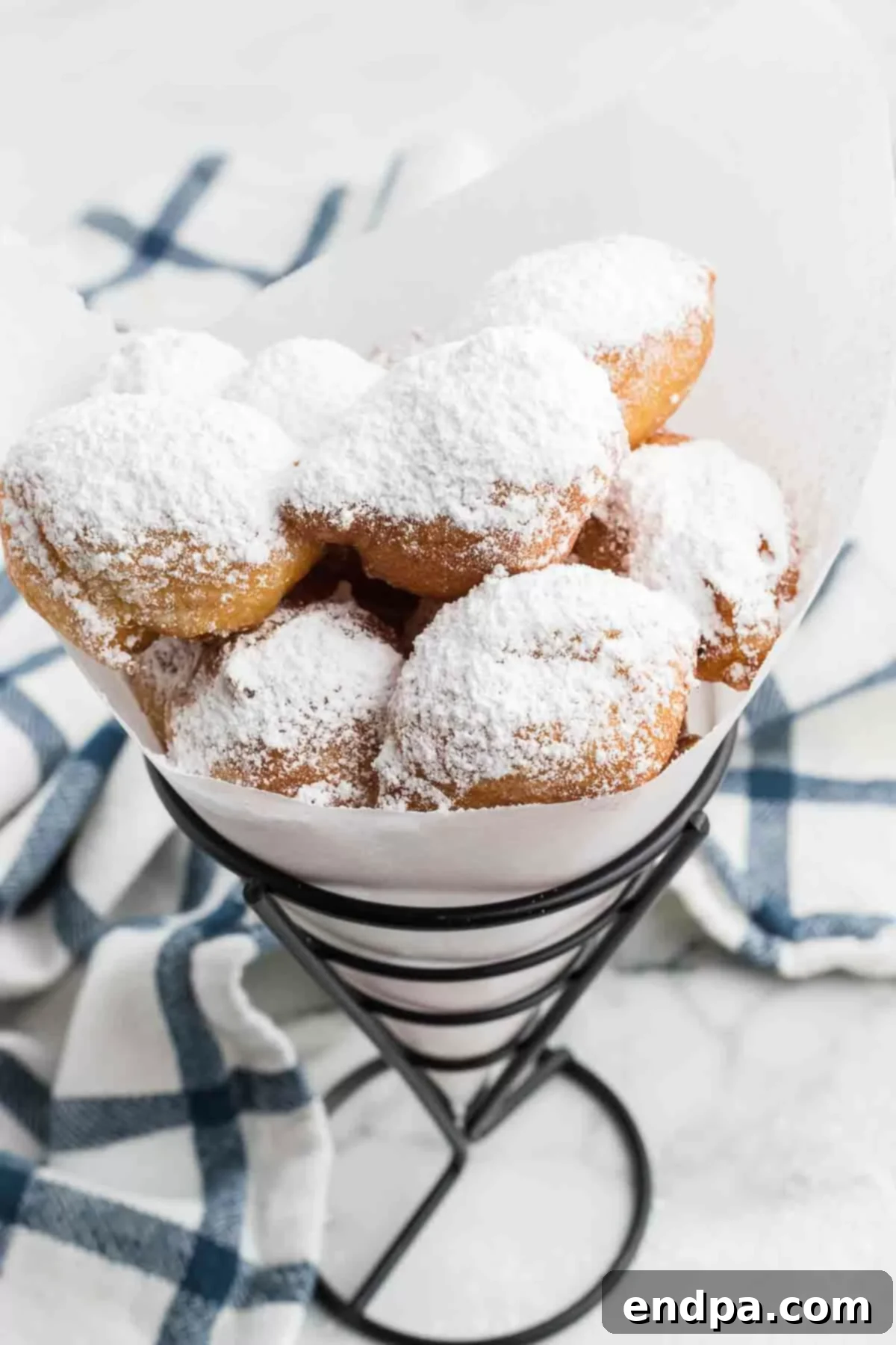 Classic Italian Zeppole Recipe 2 Italian donuts in container topped with powdered sugar.