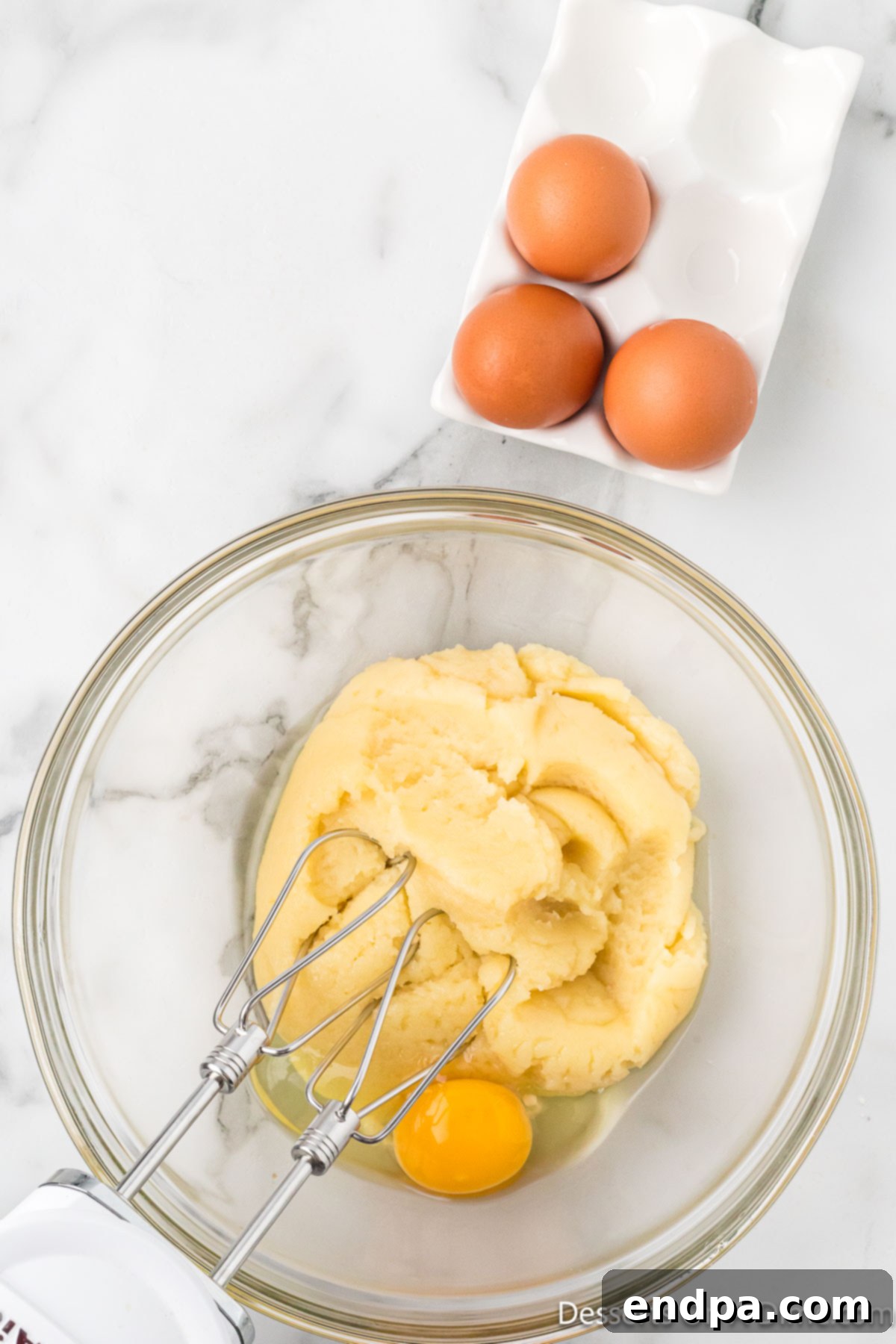 Classic Italian Zeppole Recipe 6 Eggs mixed into dough in bowl.