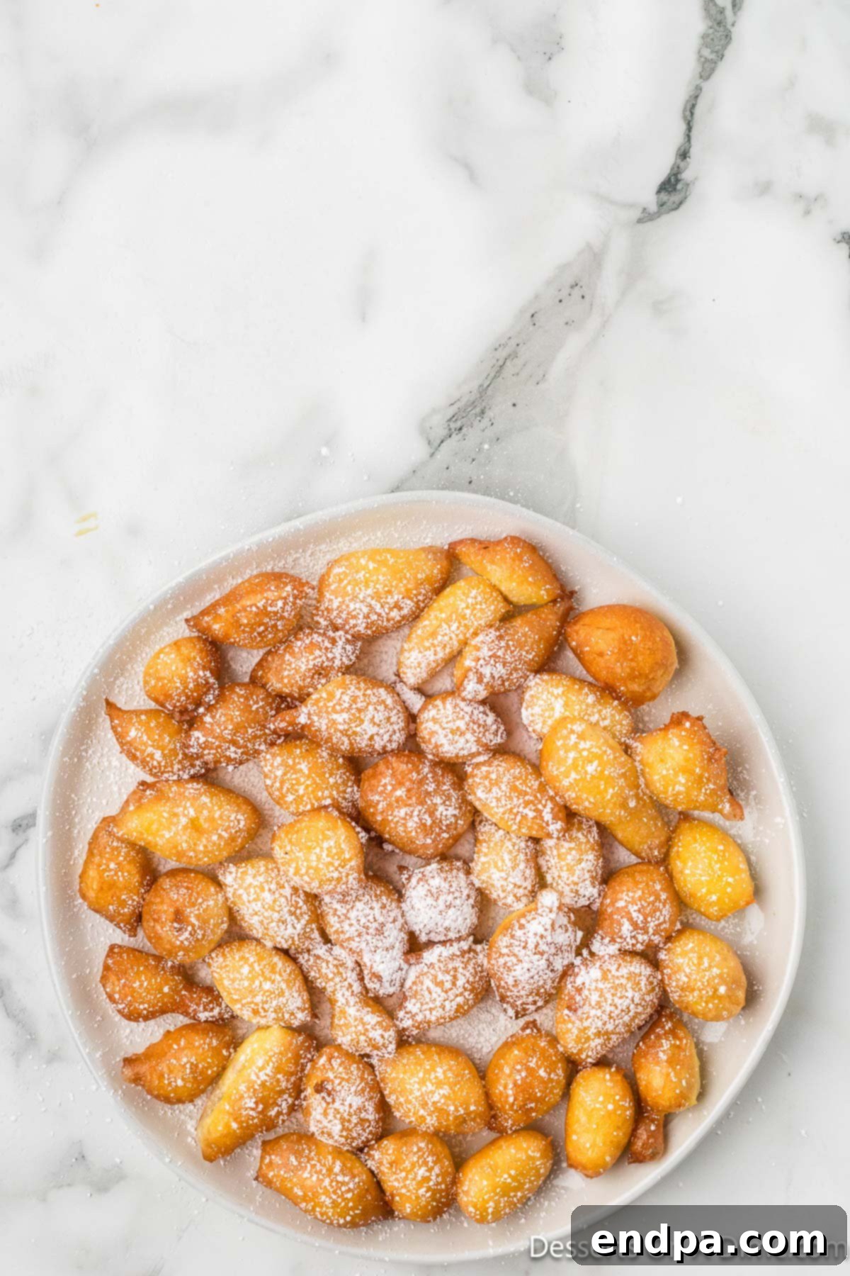 Classic Italian Zeppole Recipe 9 Italian Donuts on plate sprinkled with powdered sugar.