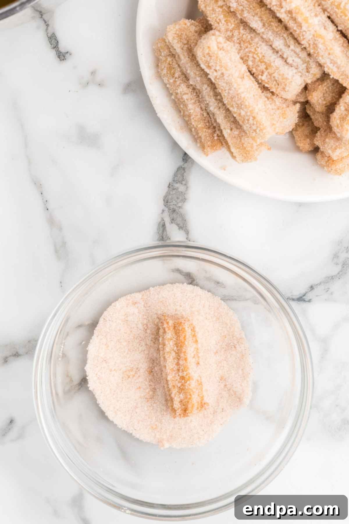 Warm churro bites being rolled in cinnamon sugar mixture.