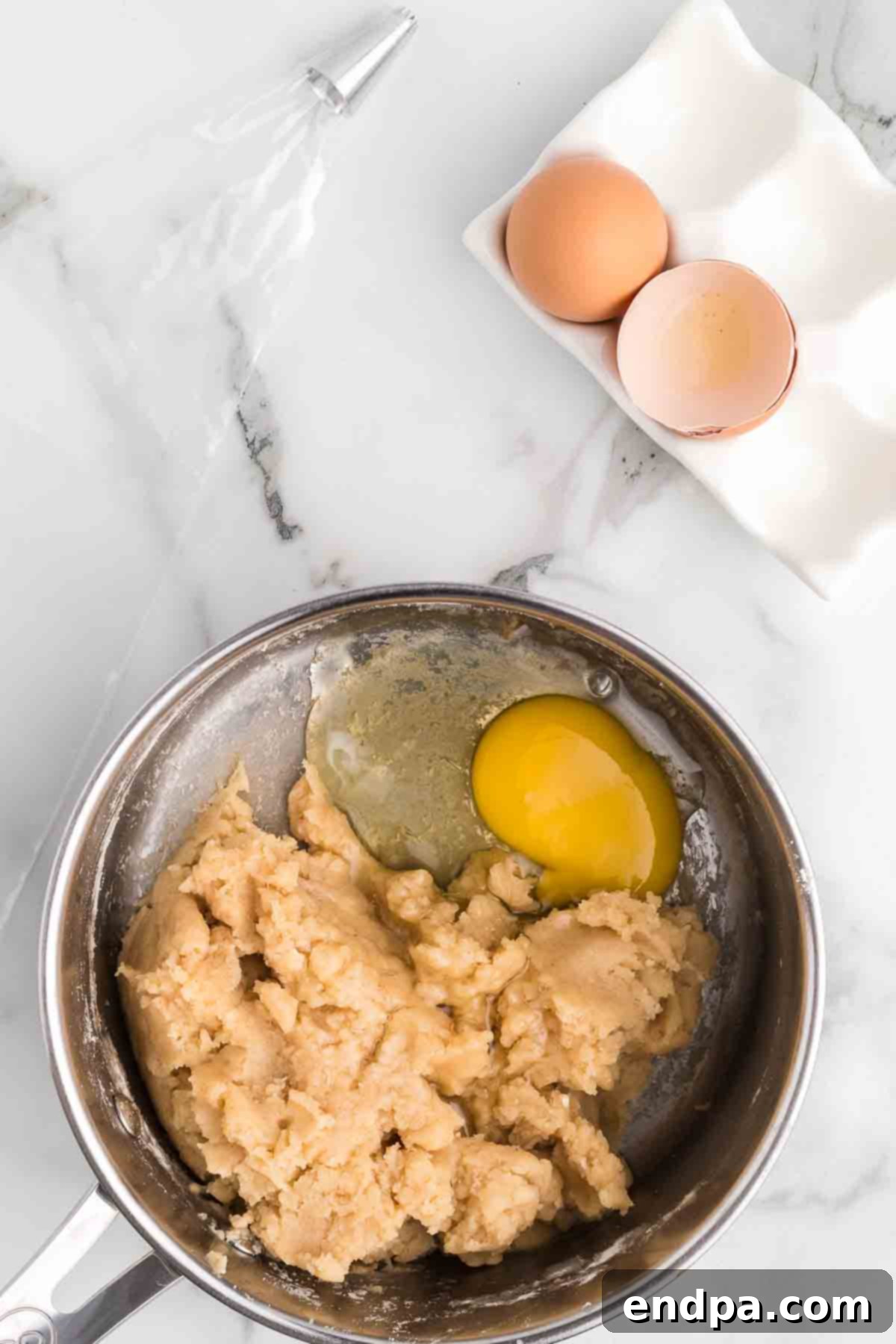 Eggs being added one by one to the cooled churro dough.