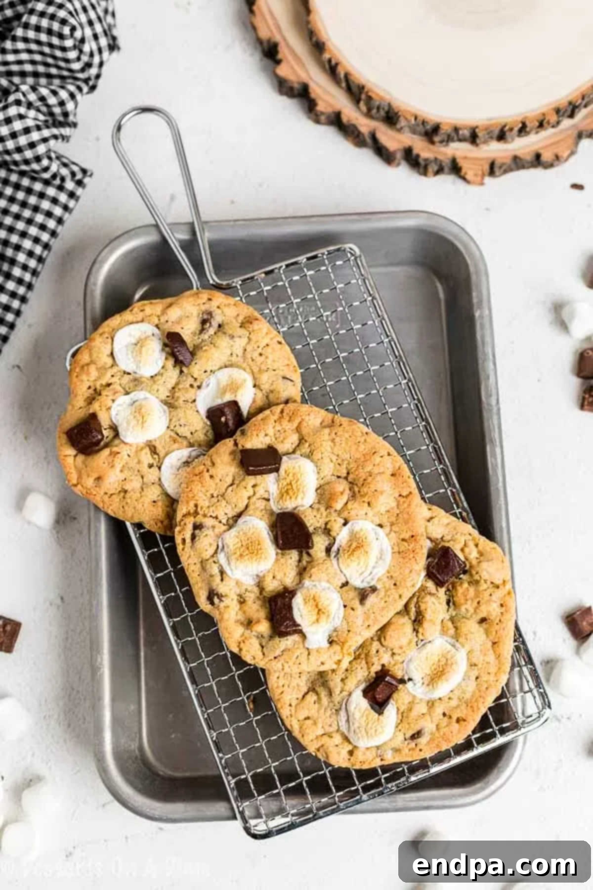 Everything you love about s'mores is packed into this tasty S'mores Cookies Recipe. Each bite is ooey gooey with lots of chocolate, marshmallows and more! A close-up of freshly baked s'mores cookies, showcasing their melted chocolate and toasted marshmallows, resting on a cooling rack.