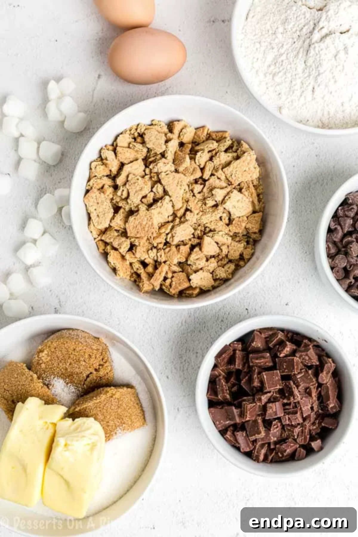 Everything you love about s'mores is packed into this tasty S'mores Cookies Recipe. Each bite is ooey gooey with lots of chocolate, marshmallows and more! All the necessary ingredients laid out for s'mores cookies: flour, crushed graham crackers, baking powder, salt, softened butter, brown sugar, white sugar, vanilla extract, fresh eggs, chocolate chips, mini marshmallows, and classic Hershey's milk chocolate bars.