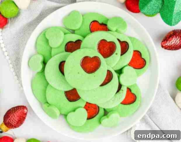 Grinchmas Dessert Delights 12 Grinch Heart Cookies, green and heart-shaped with red sprinkles.