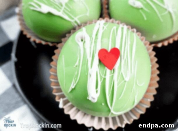 Grinchmas Dessert Delights 18 Grinch Hot Chocolate Bombs, green spheres with white drizzle and red hearts.