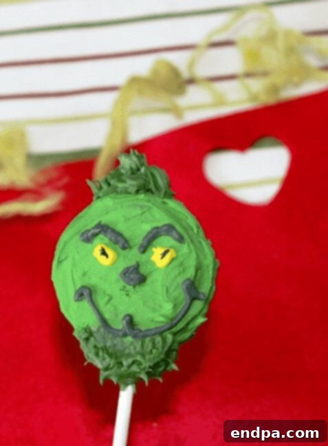 Grinchmas Dessert Delights 21 Grinch Cookie Pops on sticks, decorated with green frosting and candy hearts.