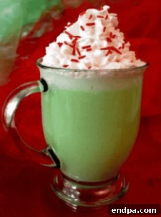 Grinchmas Dessert Delights 30 Grinch Hot Vanilla Milk in a mug with whipped cream and sprinkles.