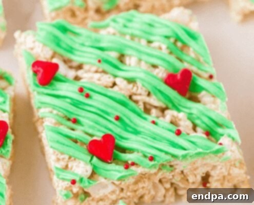 Grinchmas Dessert Delights 7 Grinch Rice Krispie Treats with green icing and red heart sprinkles.