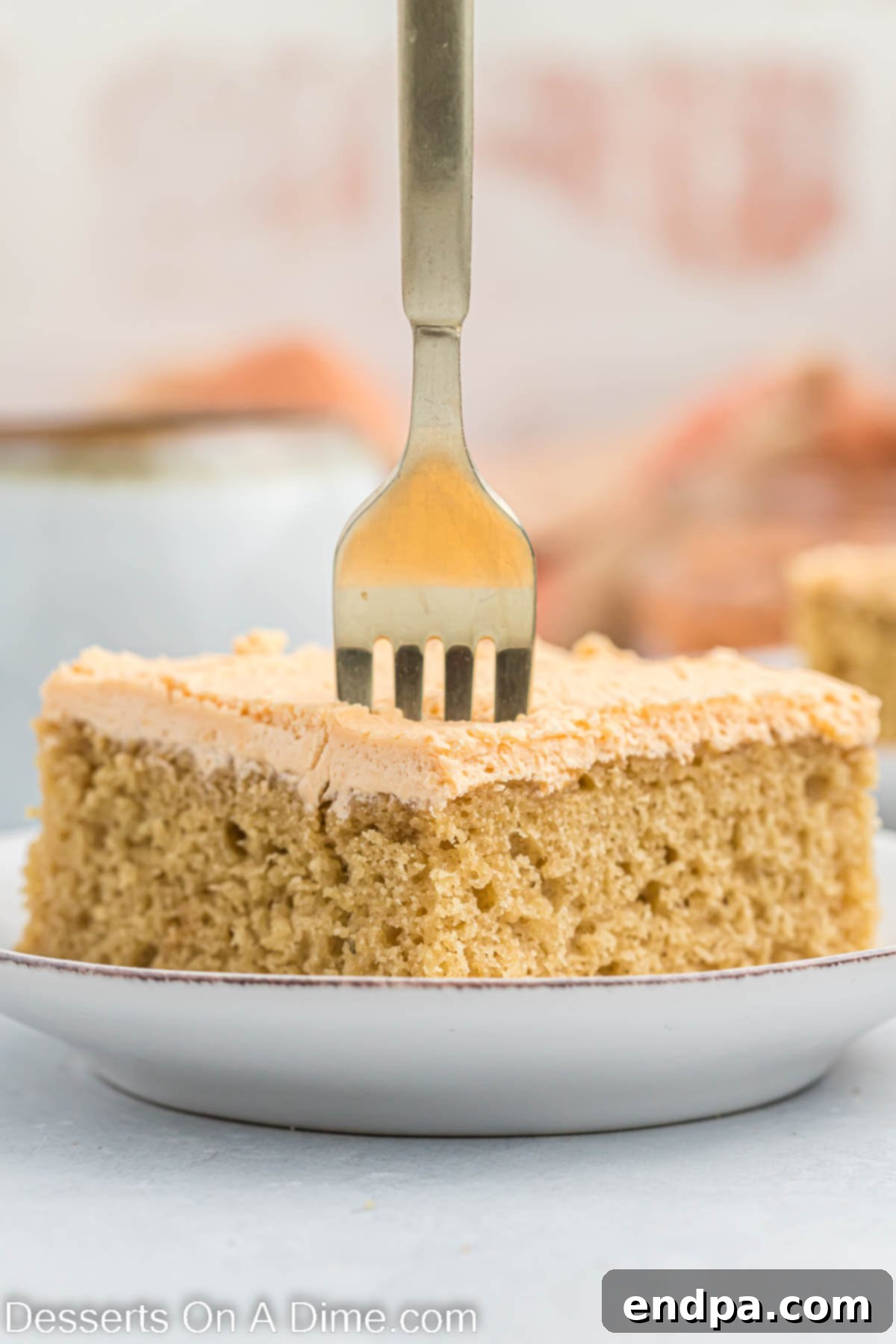 Butterscotch Bliss Cake 9 A slice of frosted butterscotch cake on a white plate, ready to be served.