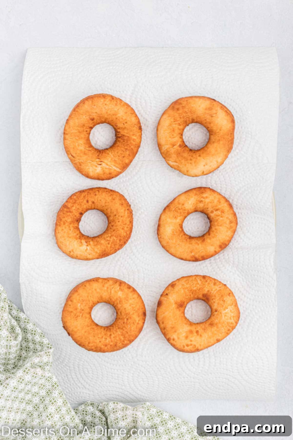 Donuts fried and placed on paper towels.