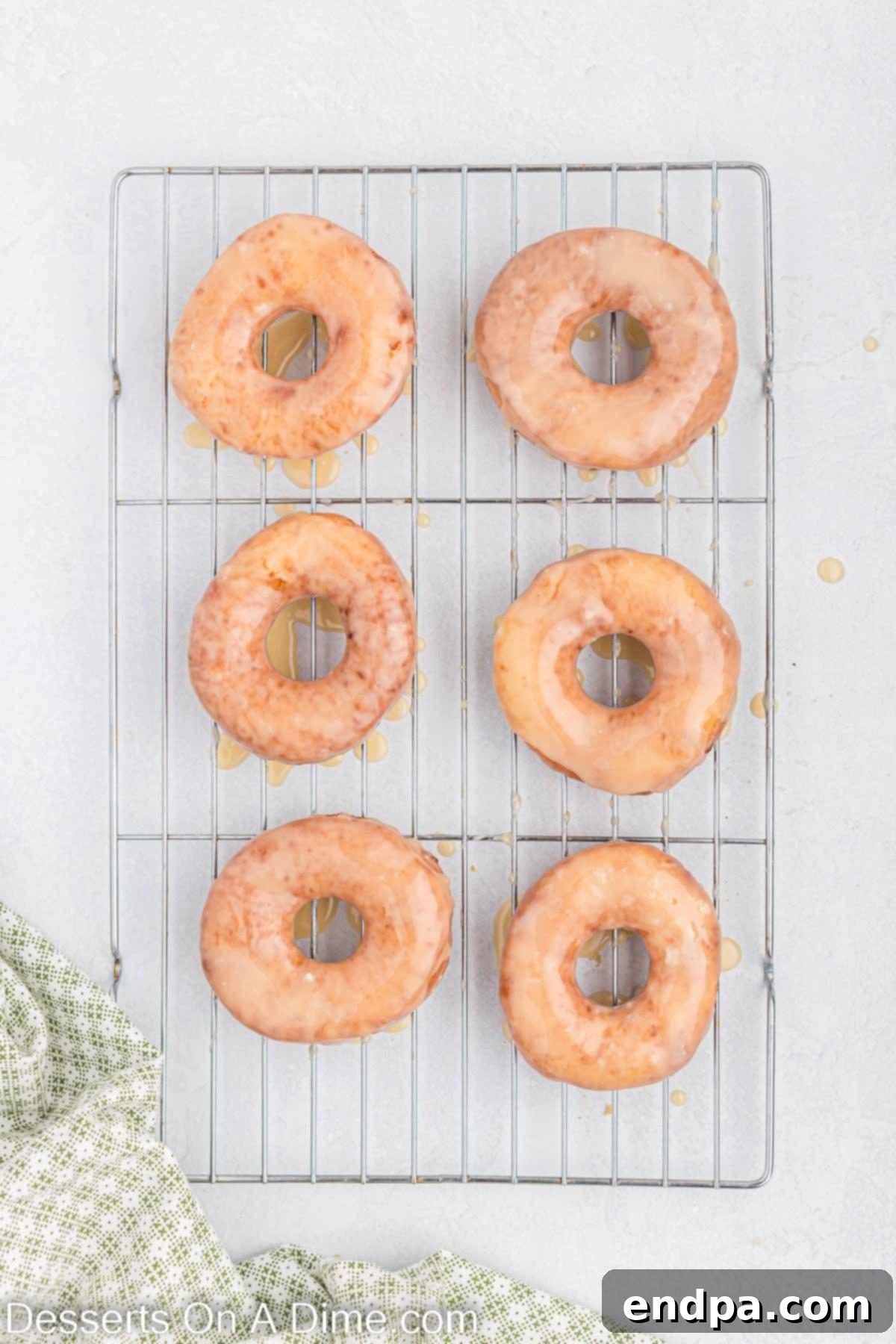Donuts dipped in glaze and placed on a wire rack.
