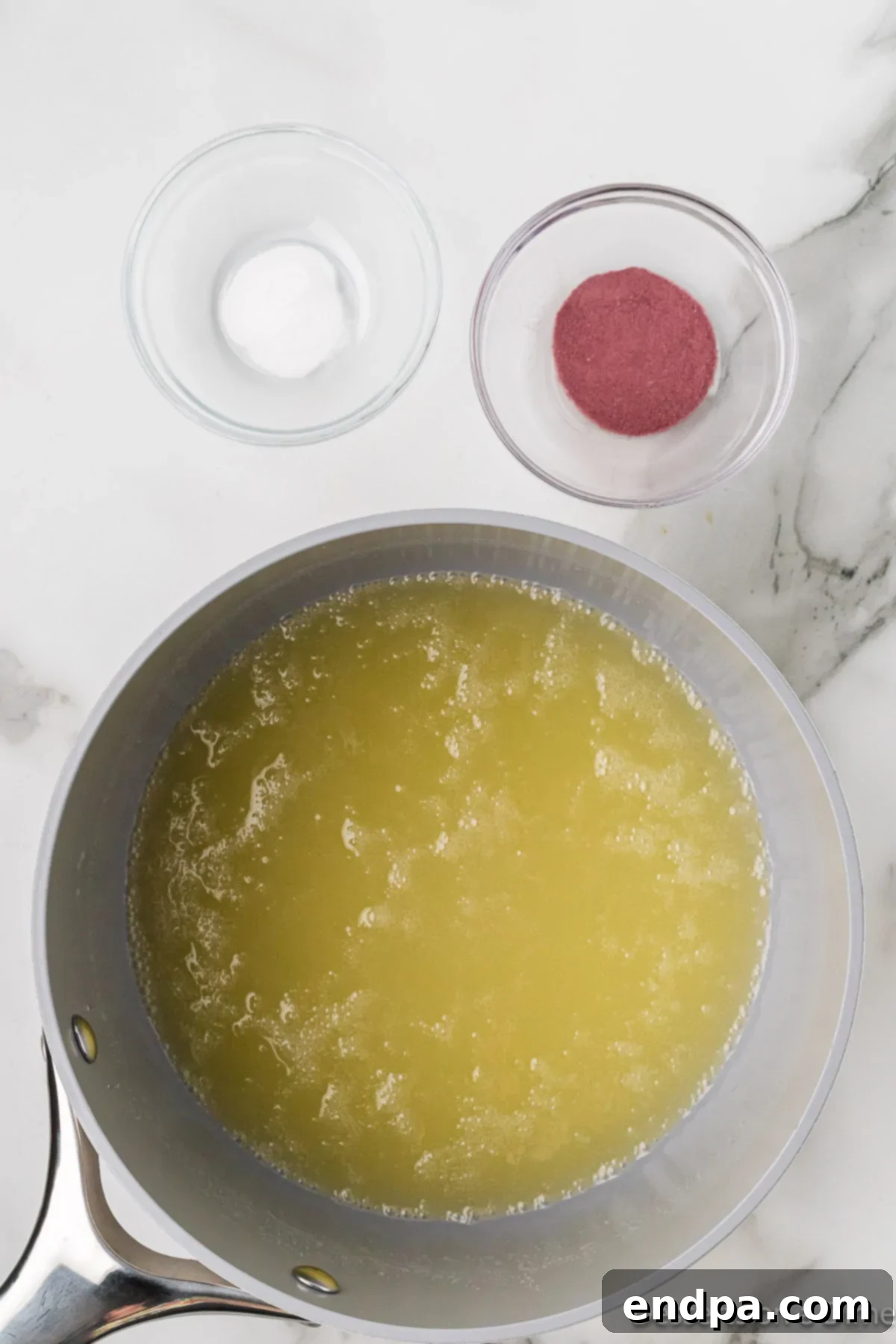 The butter, sugar, and corn syrup mixture boiling vigorously in a saucepan on the stove.