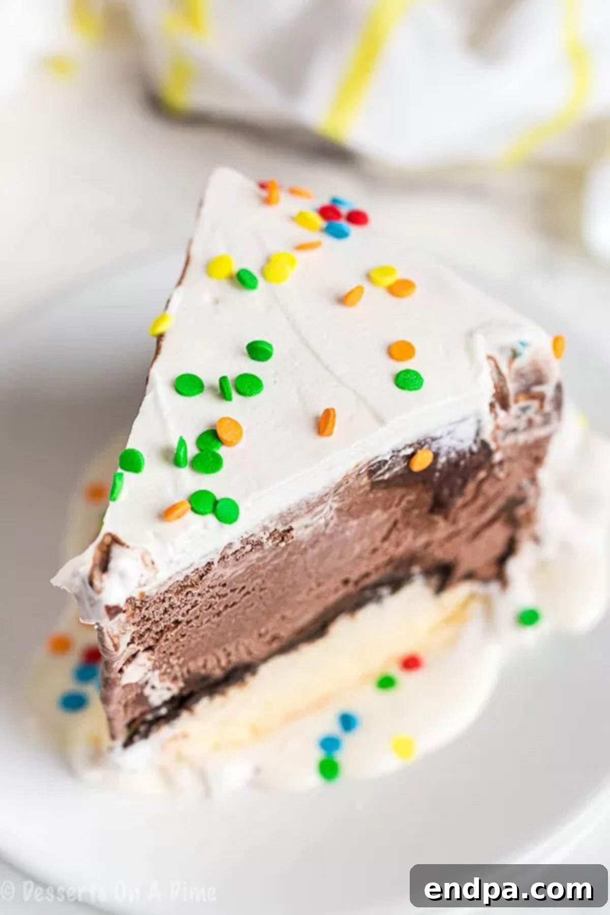 Savor Every Layer: The Perfect Homemade Ice Cream Cake Slice A tempting close-up of a slice of Dairy Queen Ice Cream Cake on a white plate, ready to be enjoyed.
