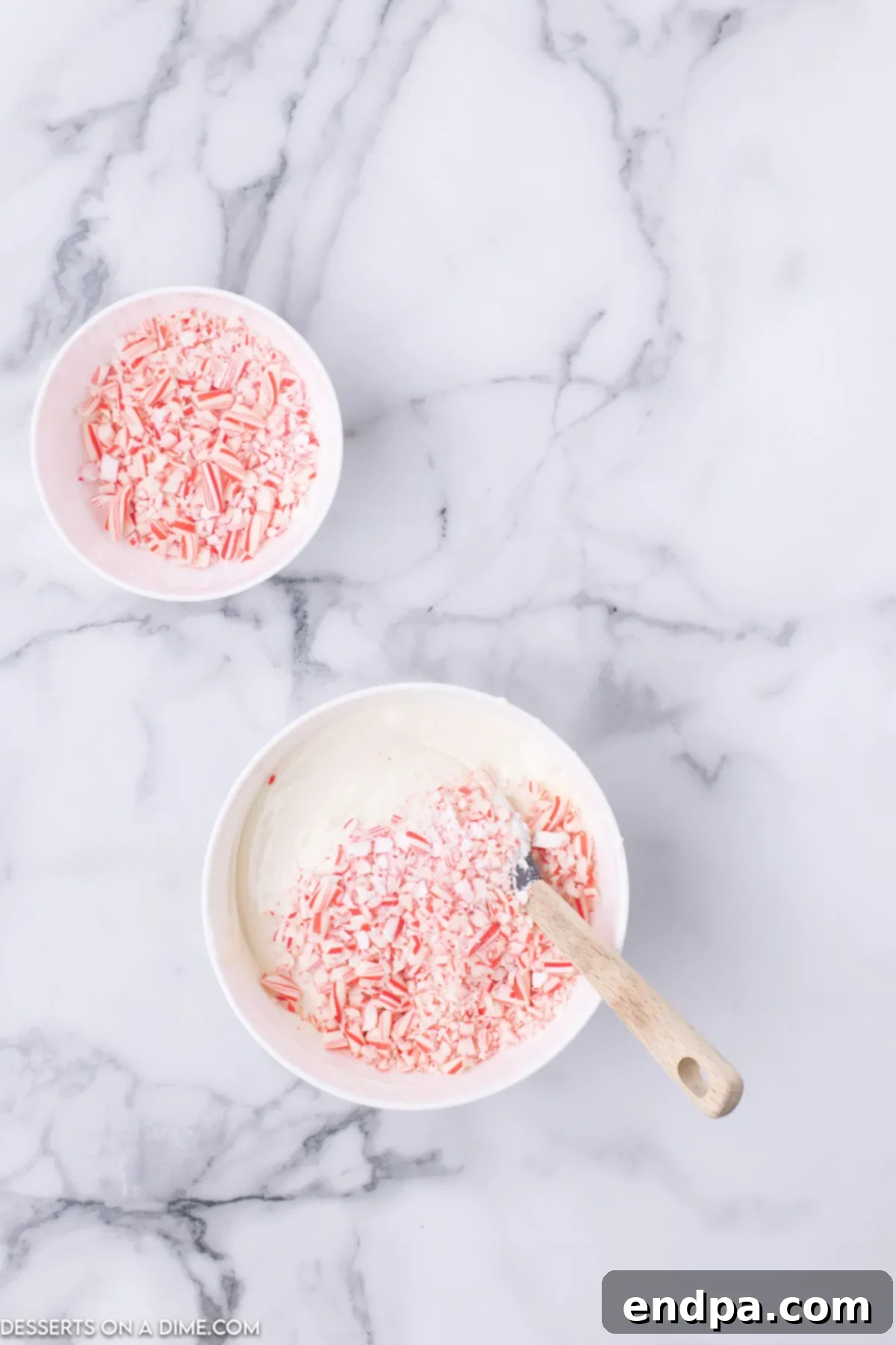 Peppermint Pop Crunch 4 Melted white chocolate mixed with crushed candy canes in a bowl.