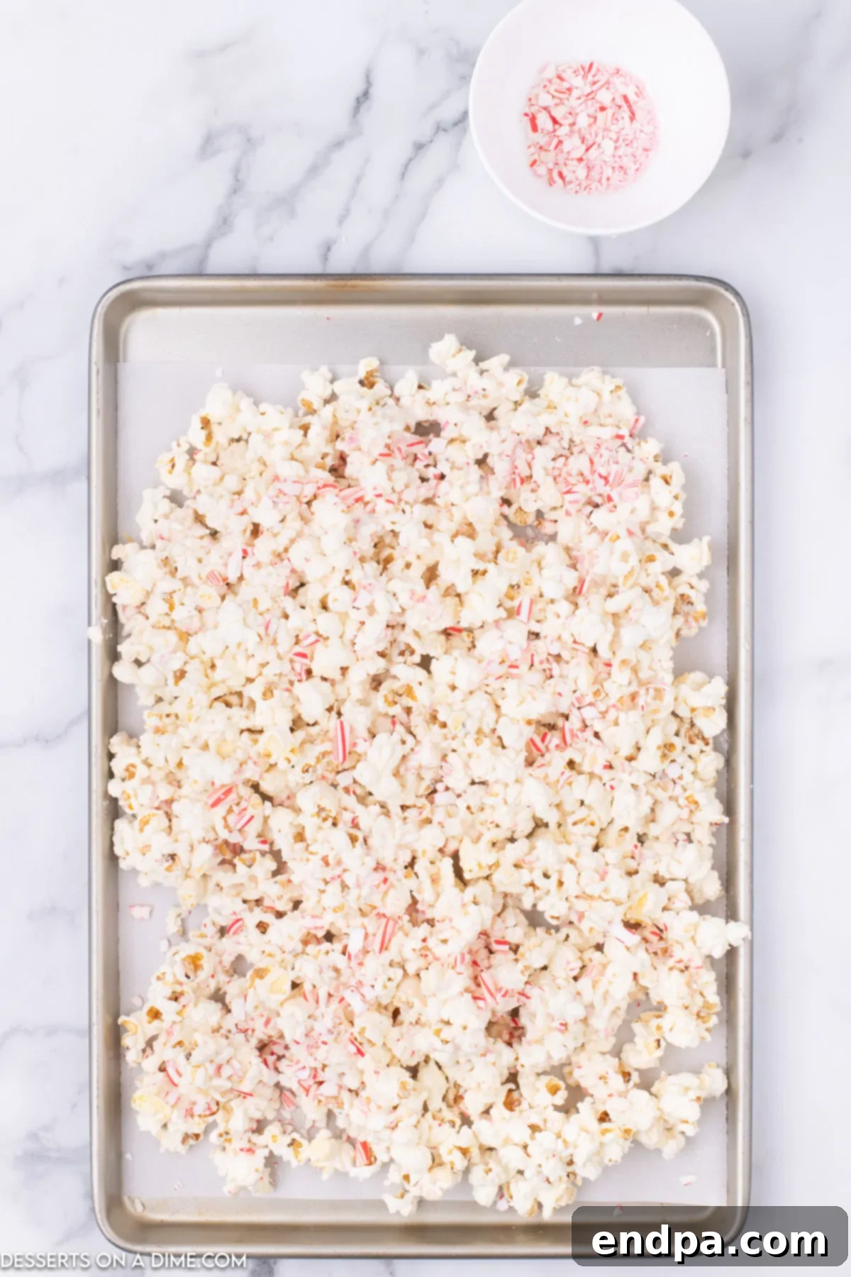 Peppermint Pop Crunch 5 Popcorn spread on a baking sheet, ready for the chocolate coating.