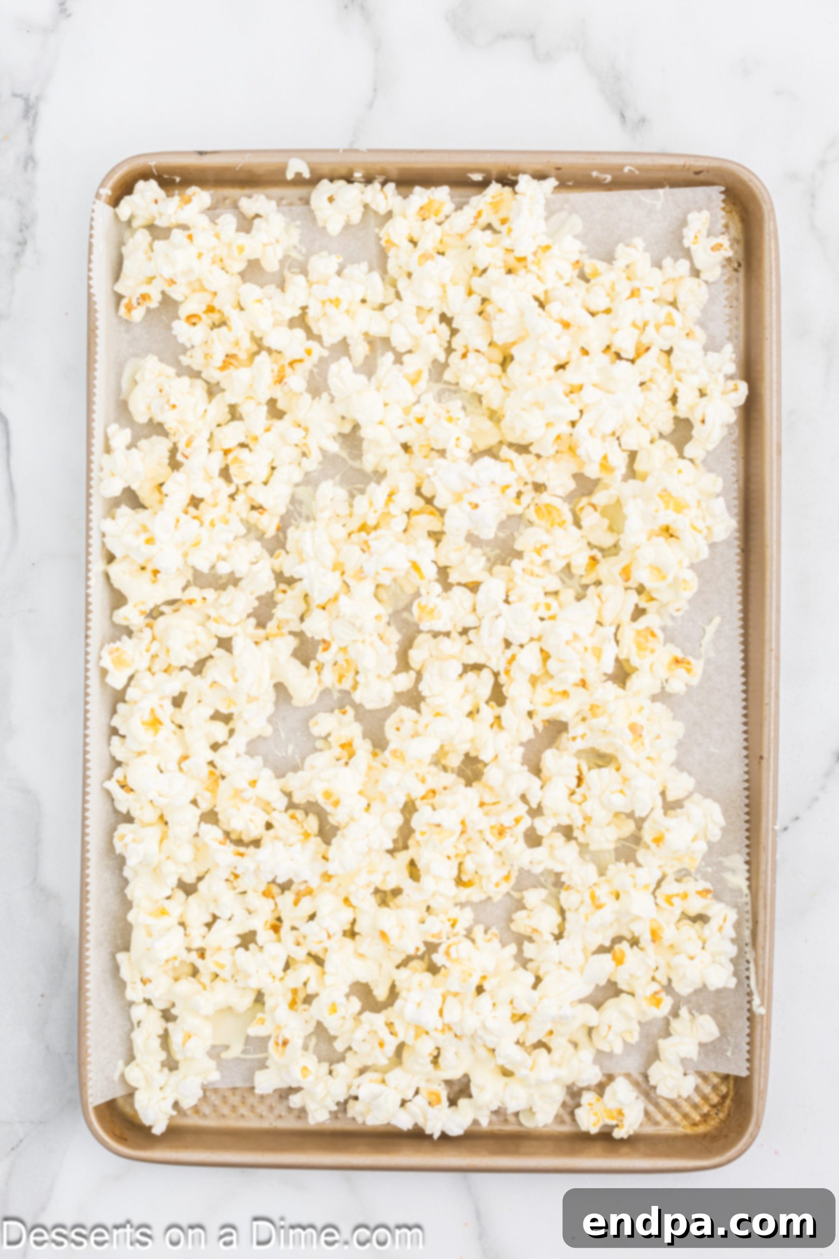 Oreo Popcorn Crunch 7 Popcorn topped with melted chocolate on baking sheet.