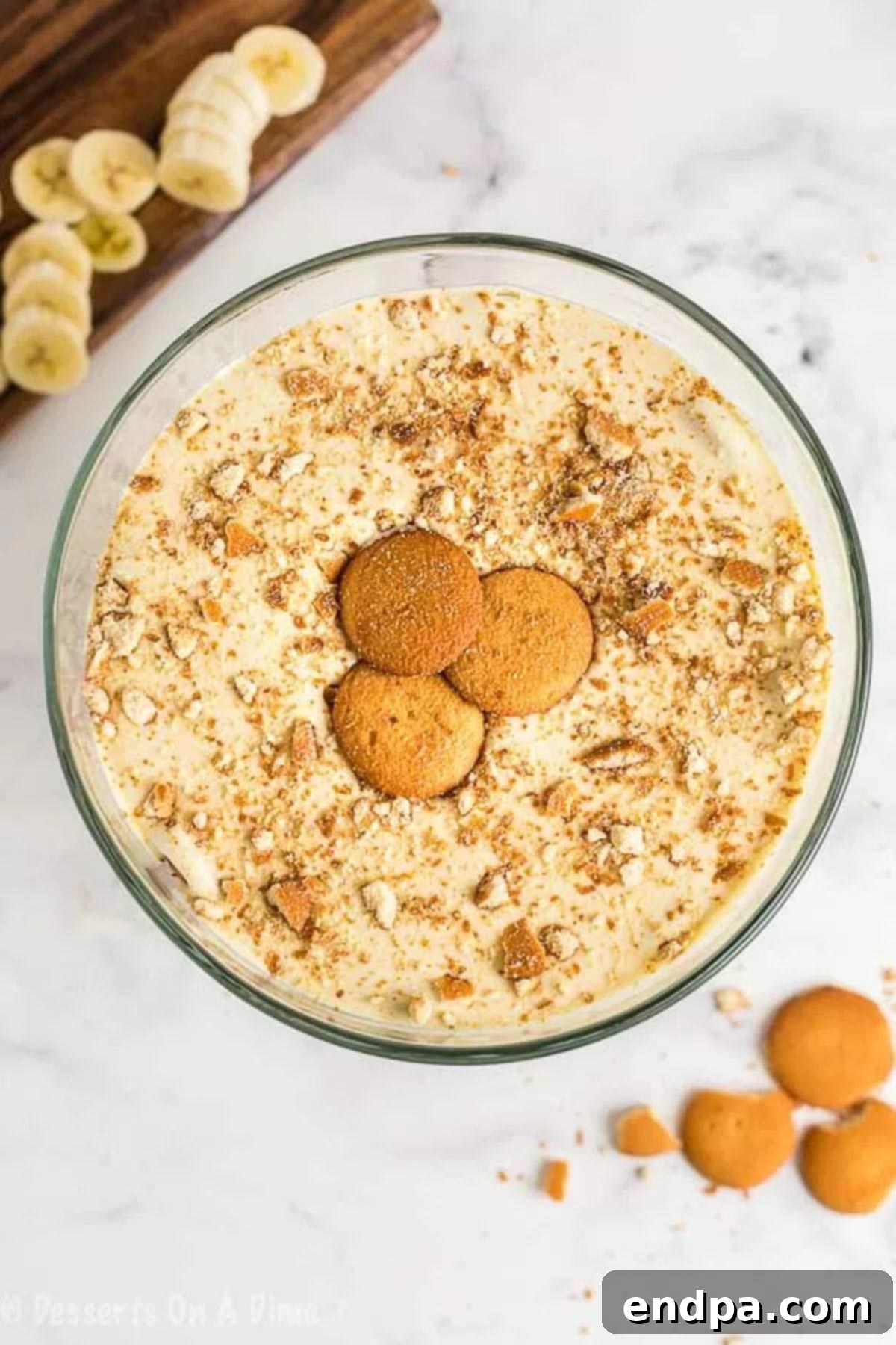 Close-up image of a layered banana pudding in a clear glass dish, topped with additional Nilla wafers for garnish, ready to be chilled.
